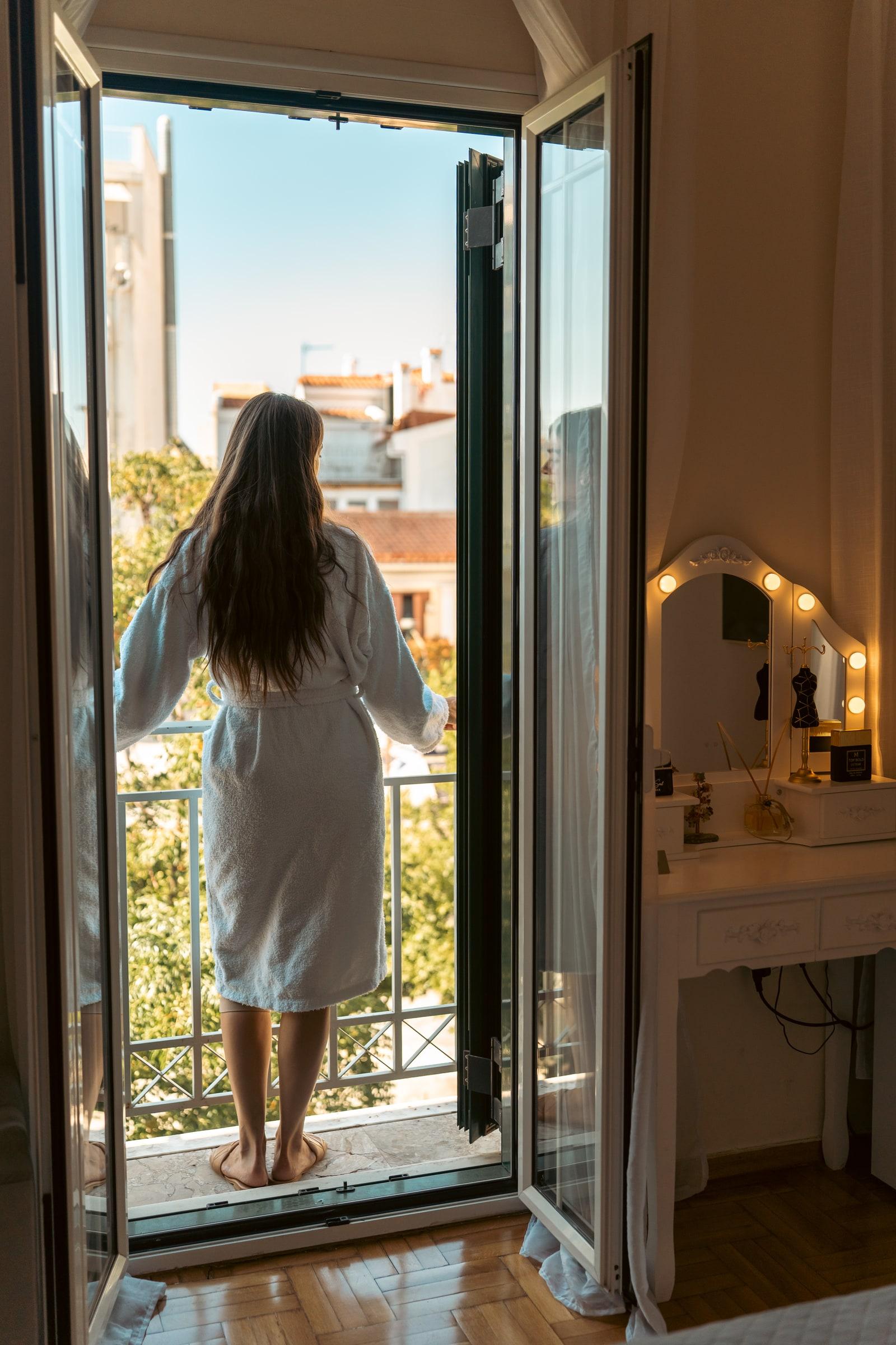 Guest in a bathrobe on the balcony, seen through the open doors