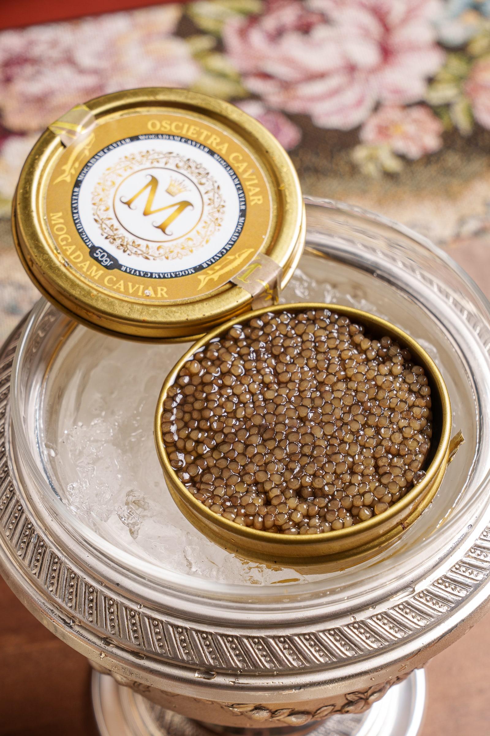 An open tin of caviar on a silver stand