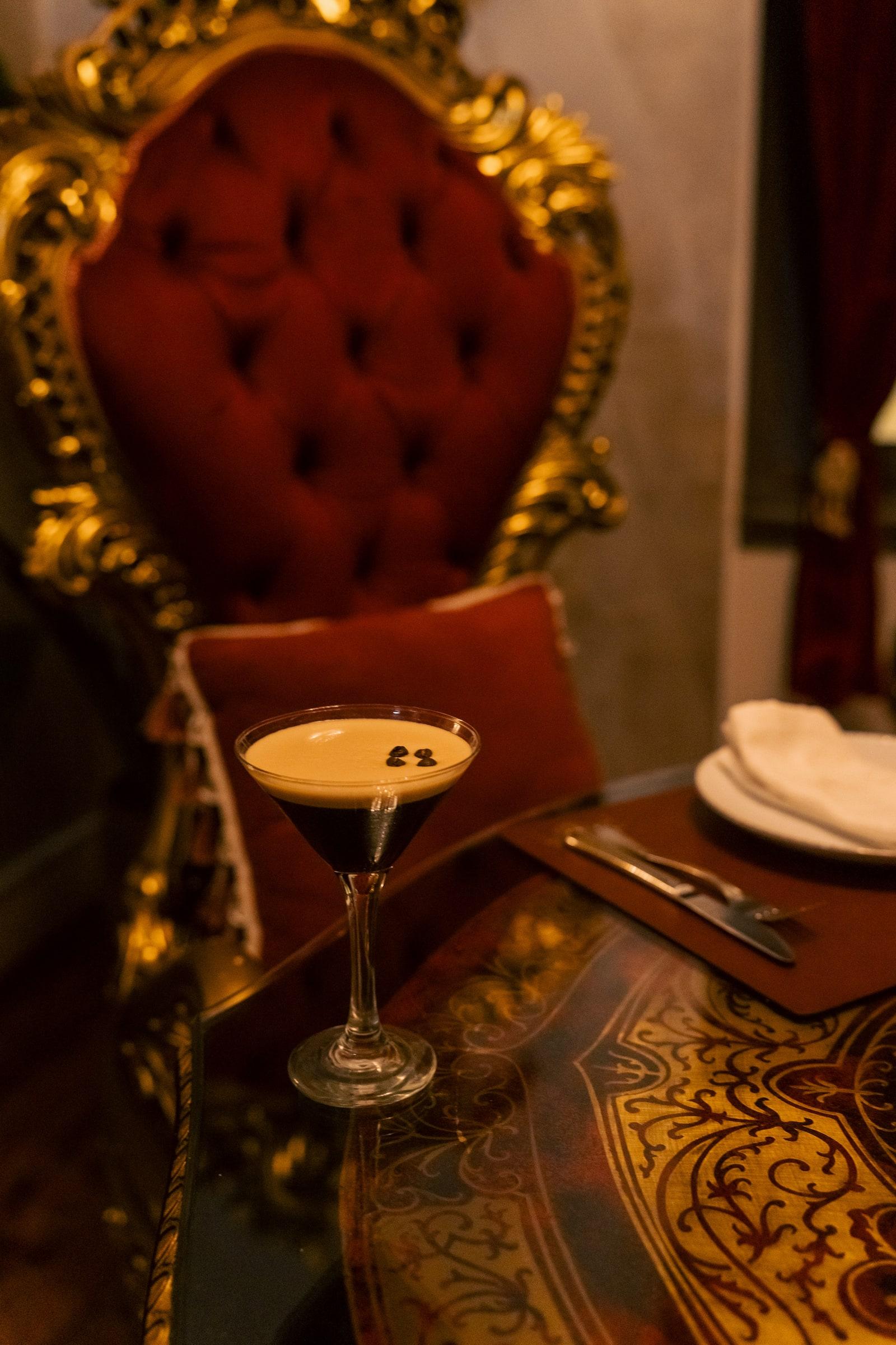An espresso martini on a red velvet armchair