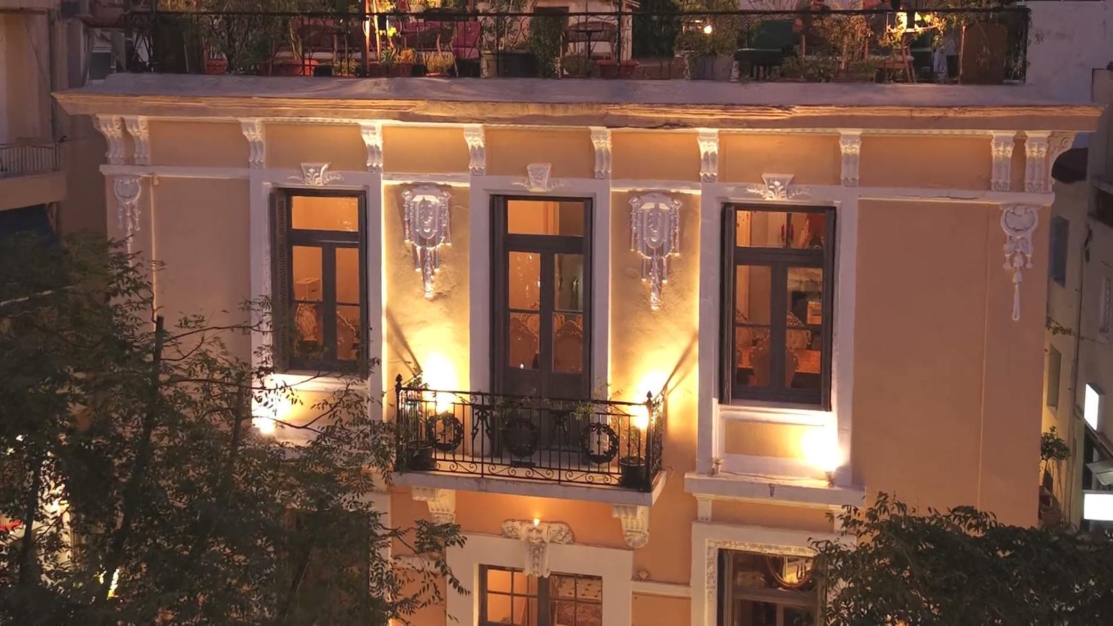 The lit neoclassical facade of ROI at blue hour, rooftop garden above