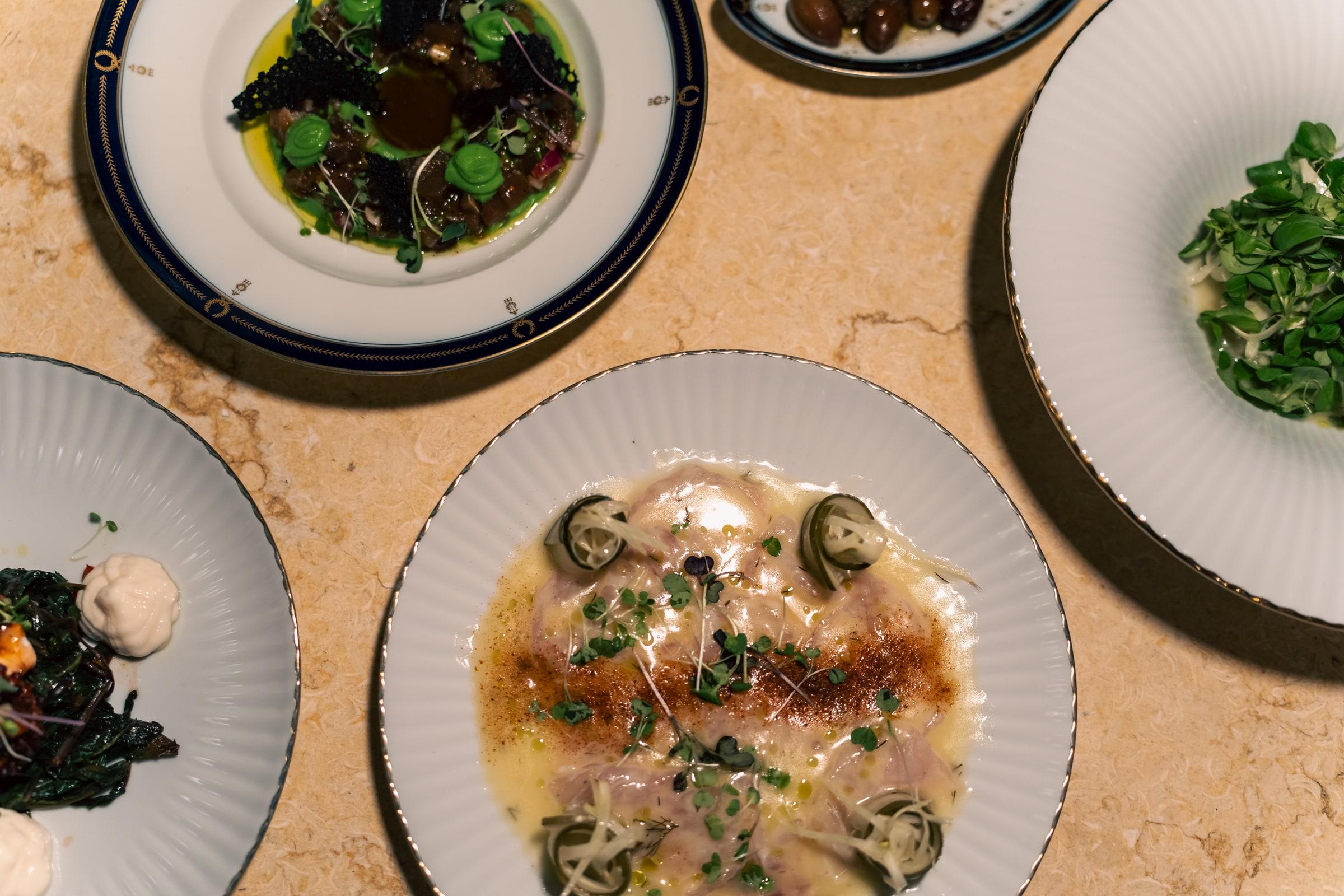 Fish carpaccio and small plates on a marble table, seen from above